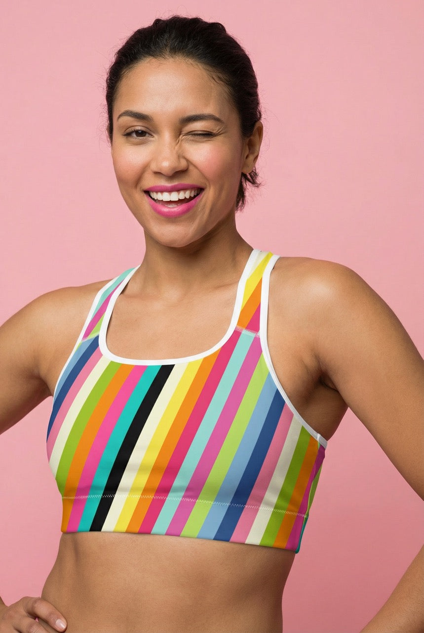 Woman wearing a colorful striped sports bra against a pink background