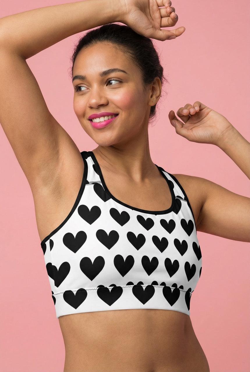 Woman wearing a sports bra with black heart pattern on a pink background
