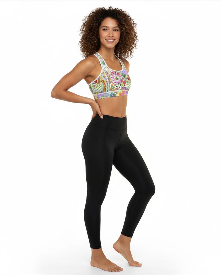 Woman wearing a colorful sports bra and black leggings on a white background