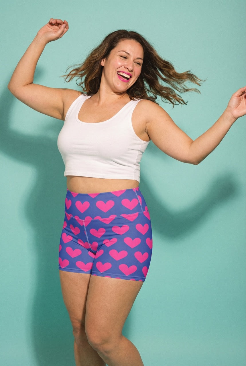 Woman wearing a white tank top and blue shorts with pink heart patterns against a light blue background