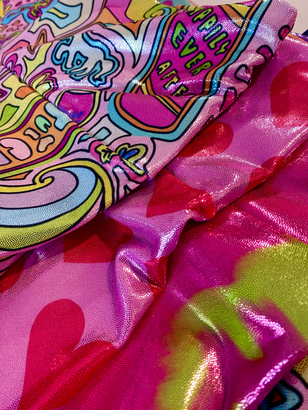 Colorful glitter shorts fabric close up of waist band. Whimasical fairytale and hearts pattern.