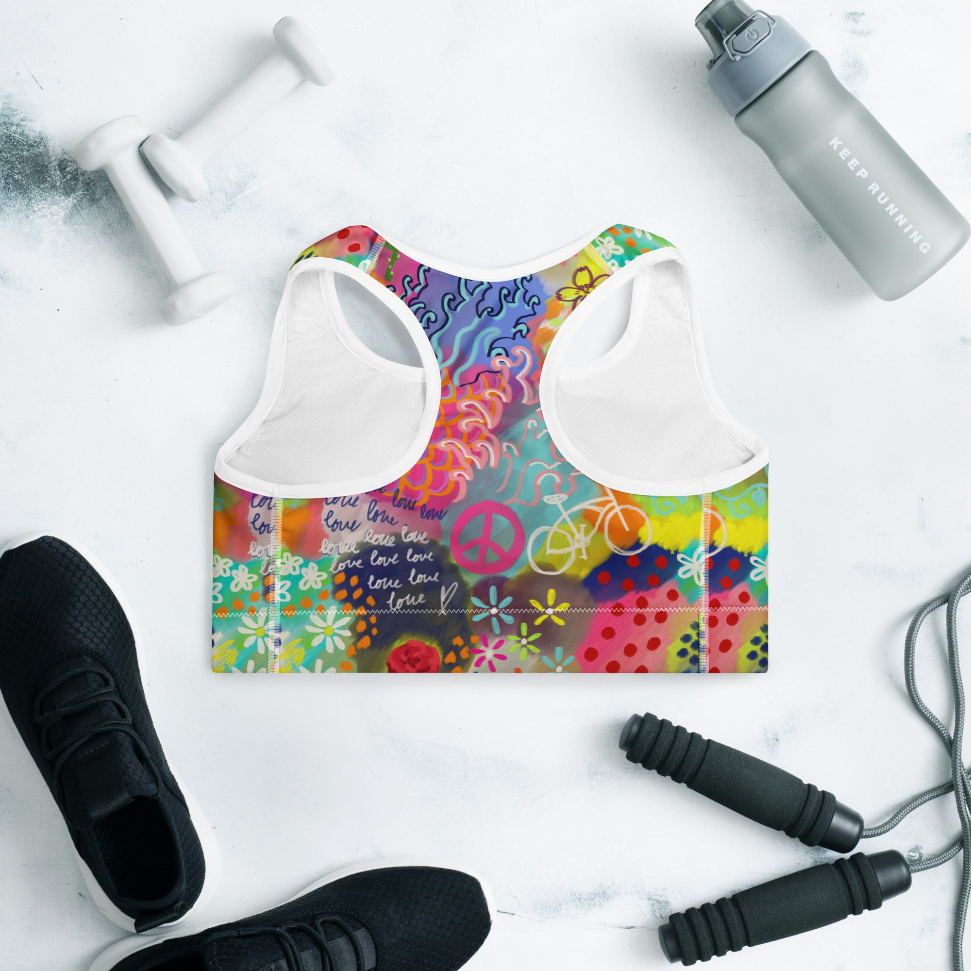 Colorful sports bra with floral and peace symbol design o a white background.
