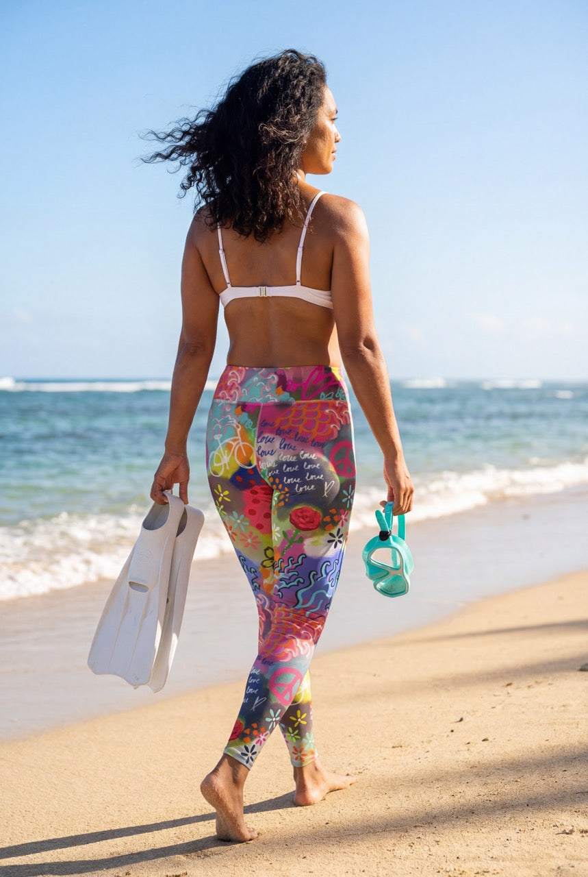 Woman in colorful leggings and white bikini top walking on a beach.