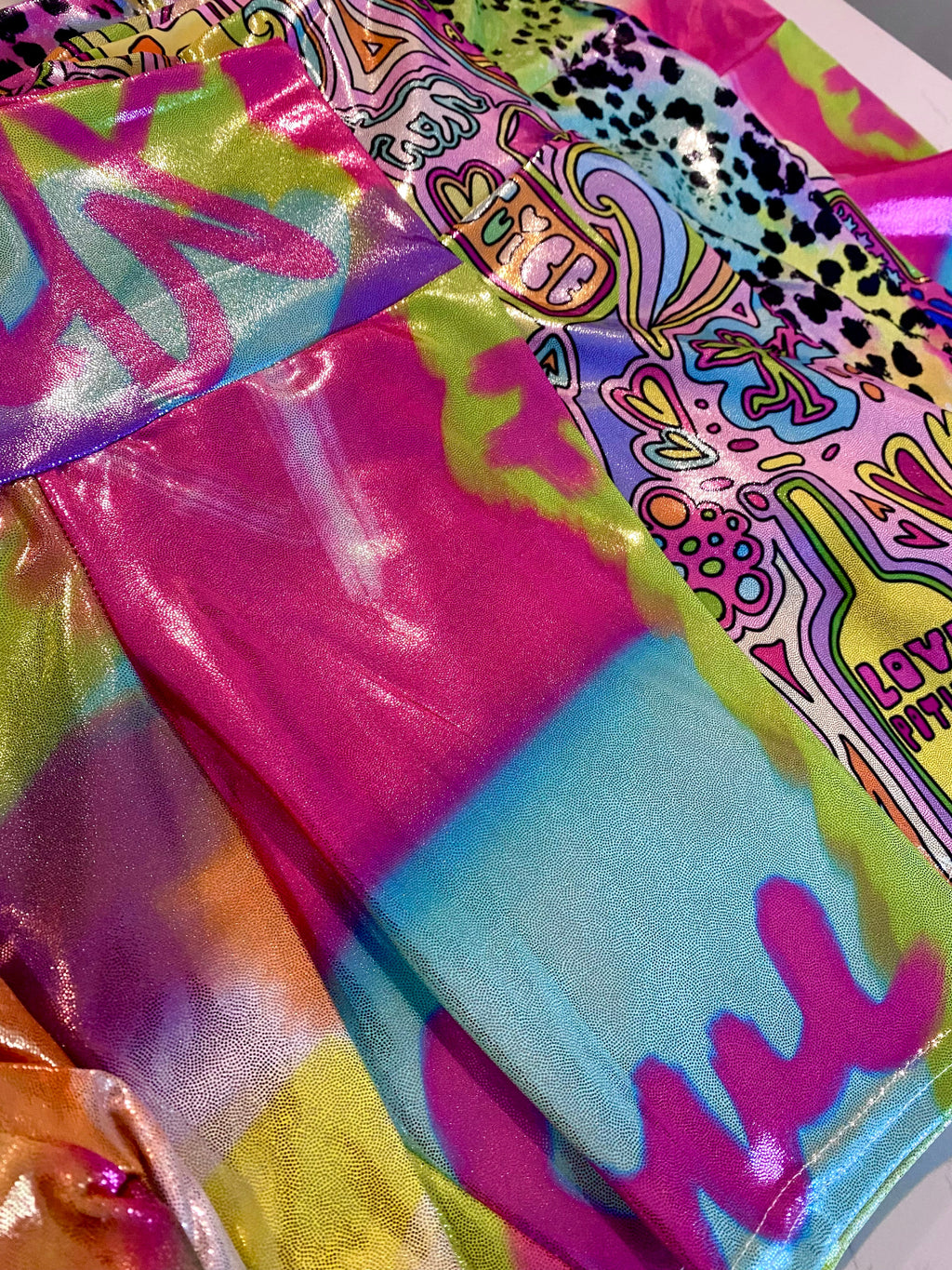 Colorful glitter shorts fabric with abstract whimsical patterns, laid flat
